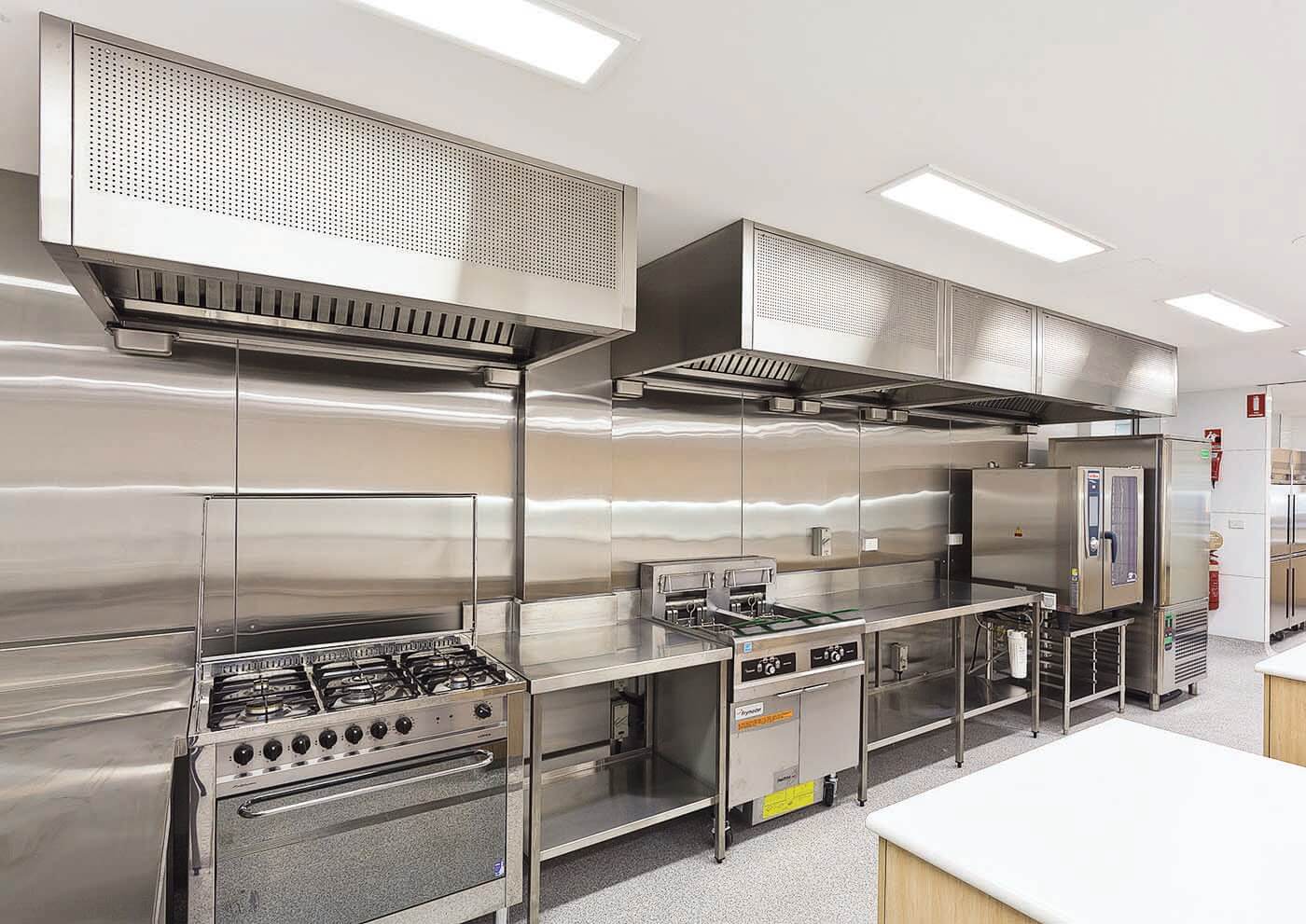 Commercial kitchen with multiple stainless steel canopy exhaust hoods